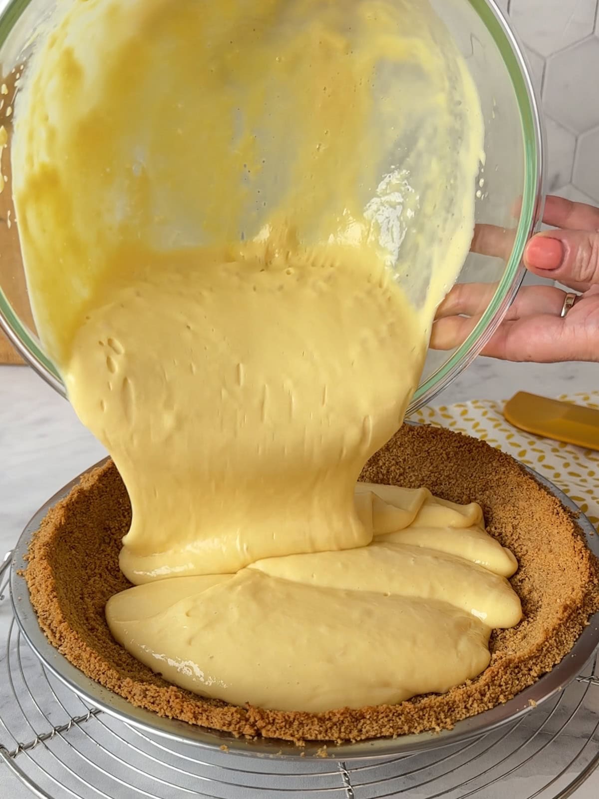 Pouring thick mango custard filling into the prepared graham cracker crust.