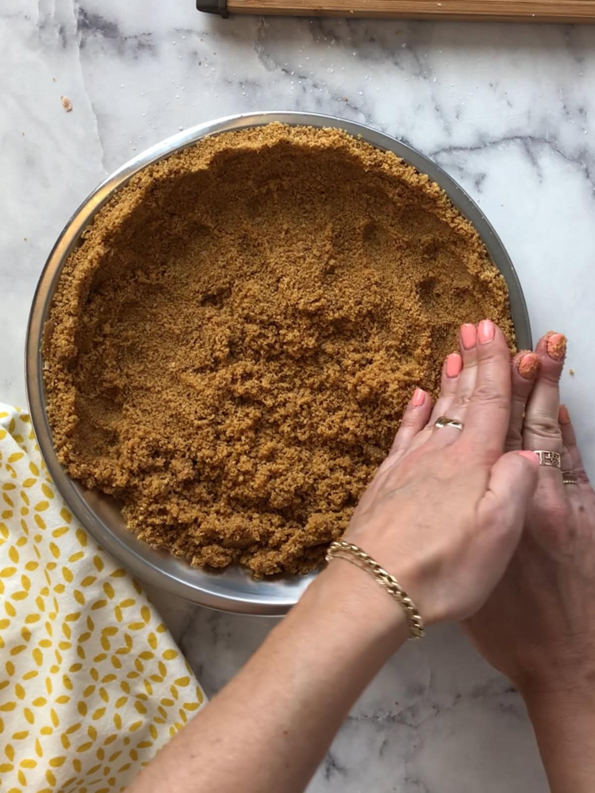 Pressing crumb mixture firmly into a pie pan to form the crust with hands.