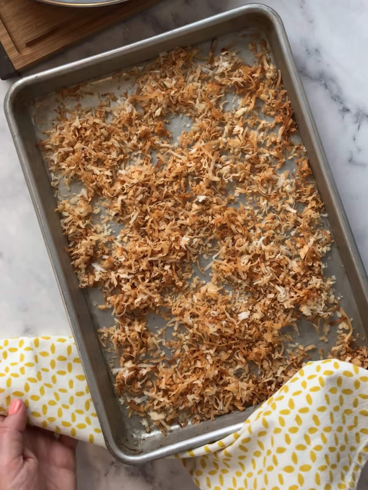 Toasted shredded coconut spread across a baking sheet, golden and fragrant.
