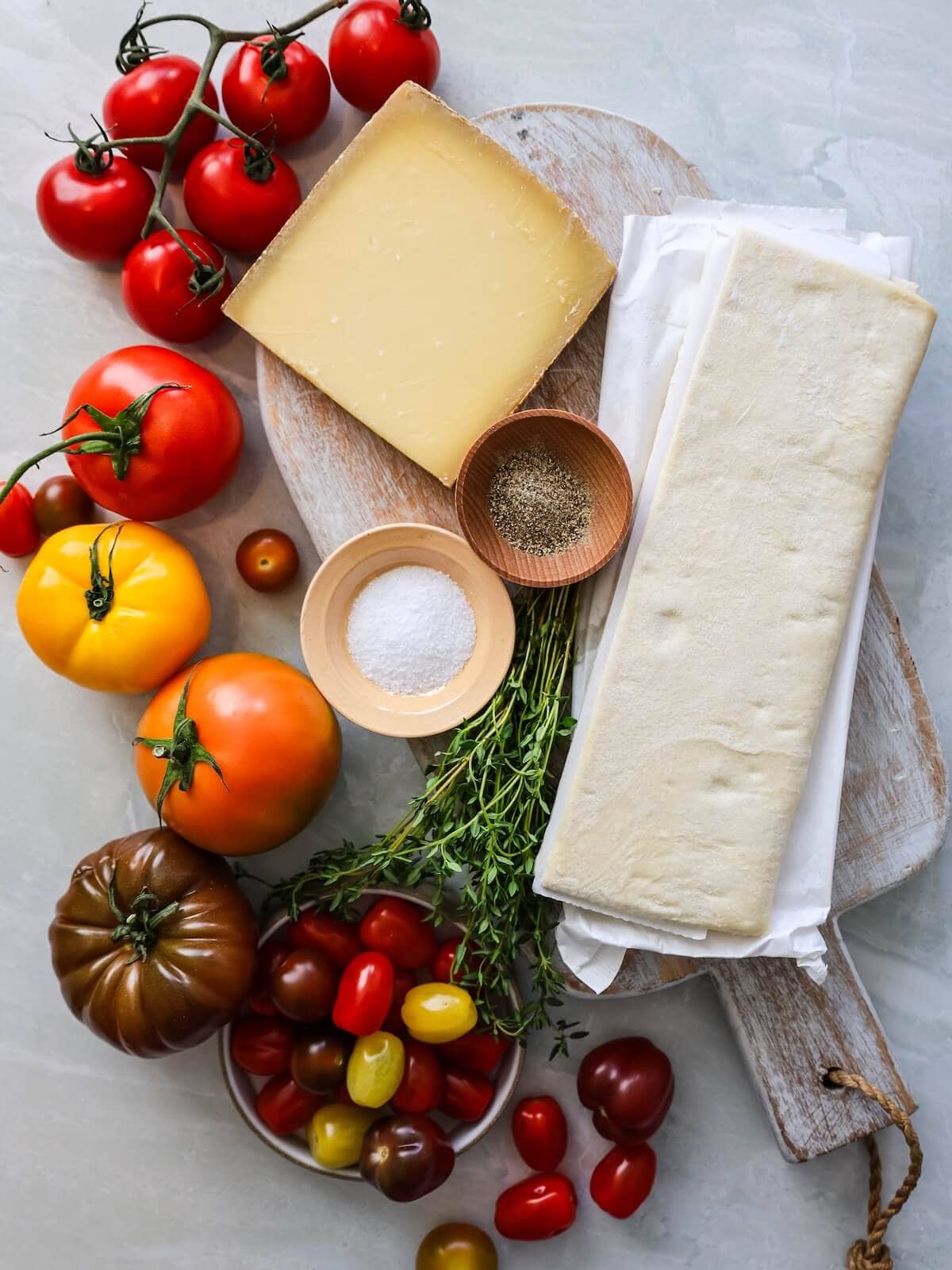 Ingredients for mini tomato tarts including tomatoes, salt, pepper, gruyere, and puff pastry.