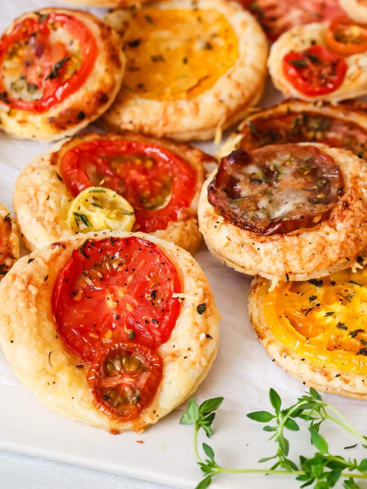 close up on mini tomato tarts with heirloom tomato slices and fresh thyme