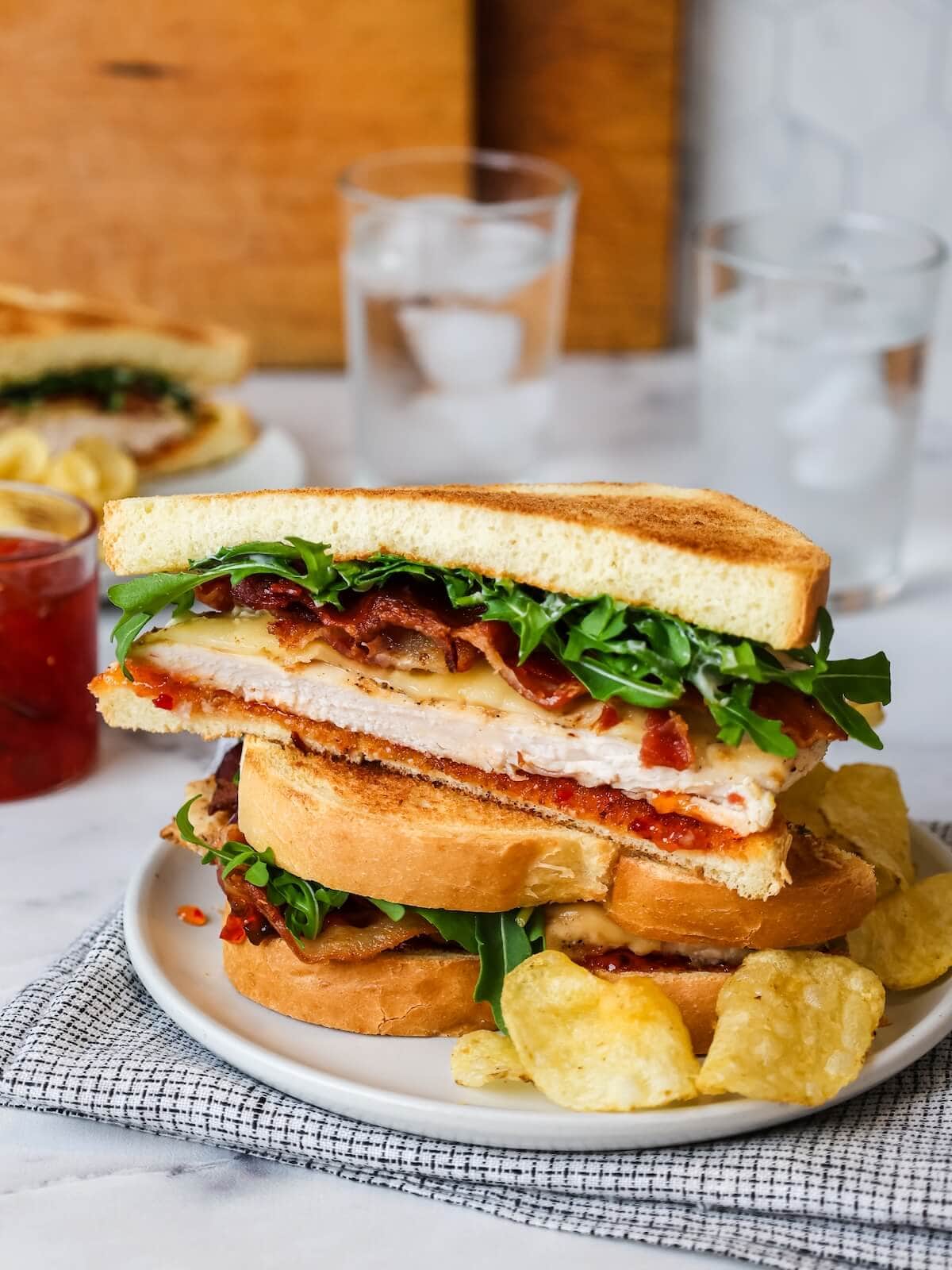 meal of sweet and spicy chicken bacon sandwiches with potato chips.
