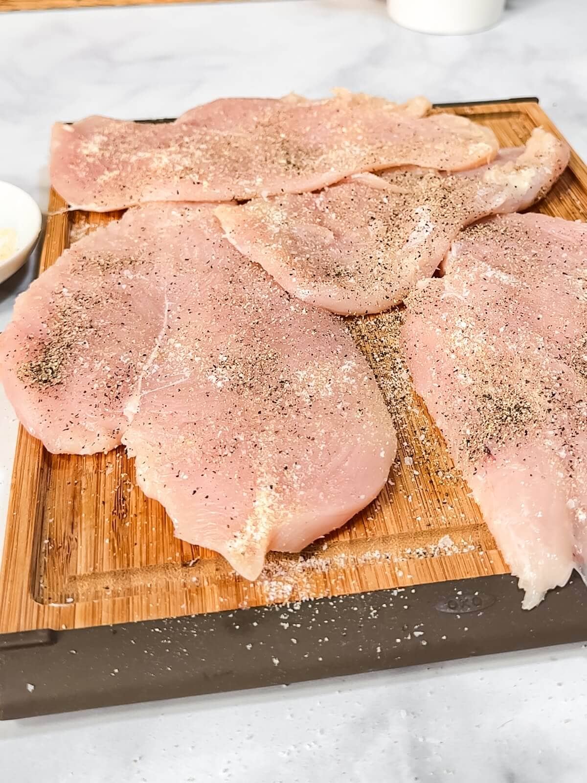 Sliced chicken on a cutting board with seasoning
