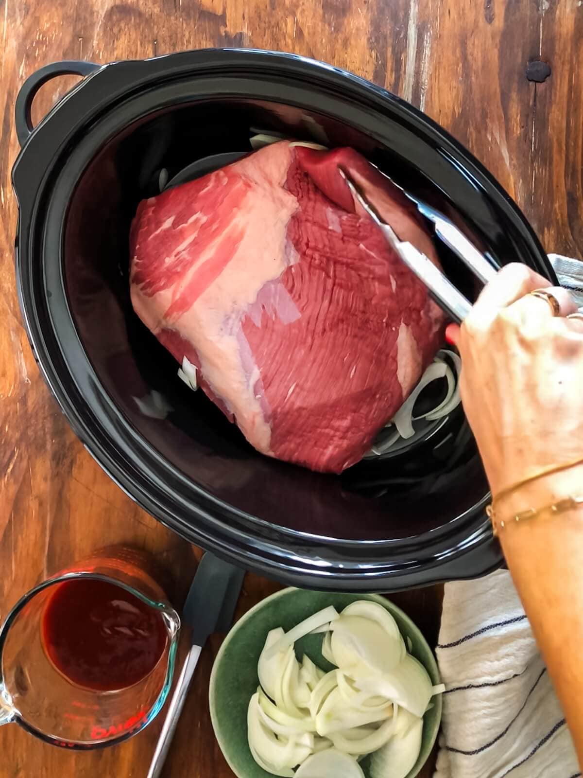 Add onions and brisket fat side up to the slow cooker.