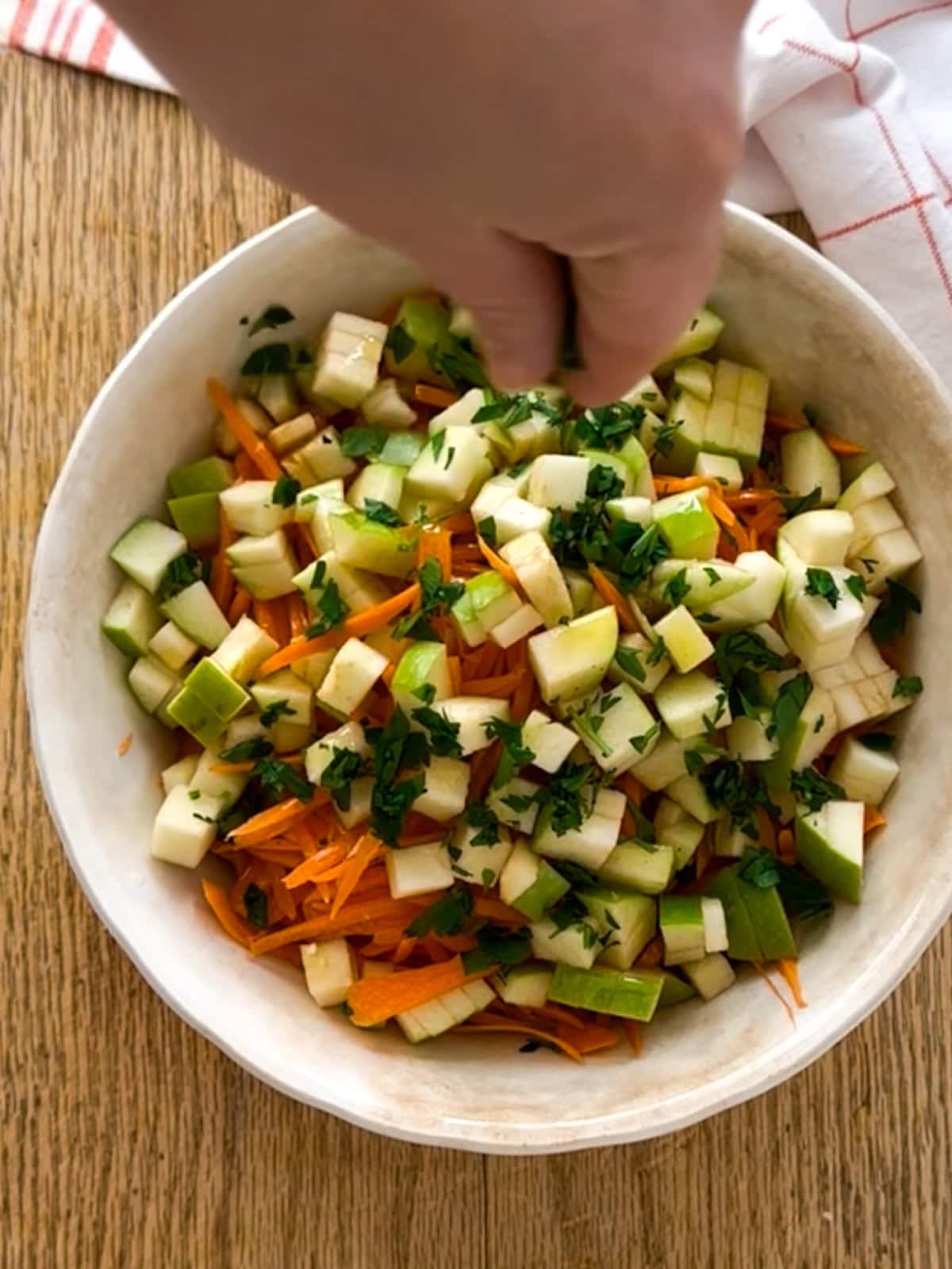 adding herbs to shredded carrot salad before serving.