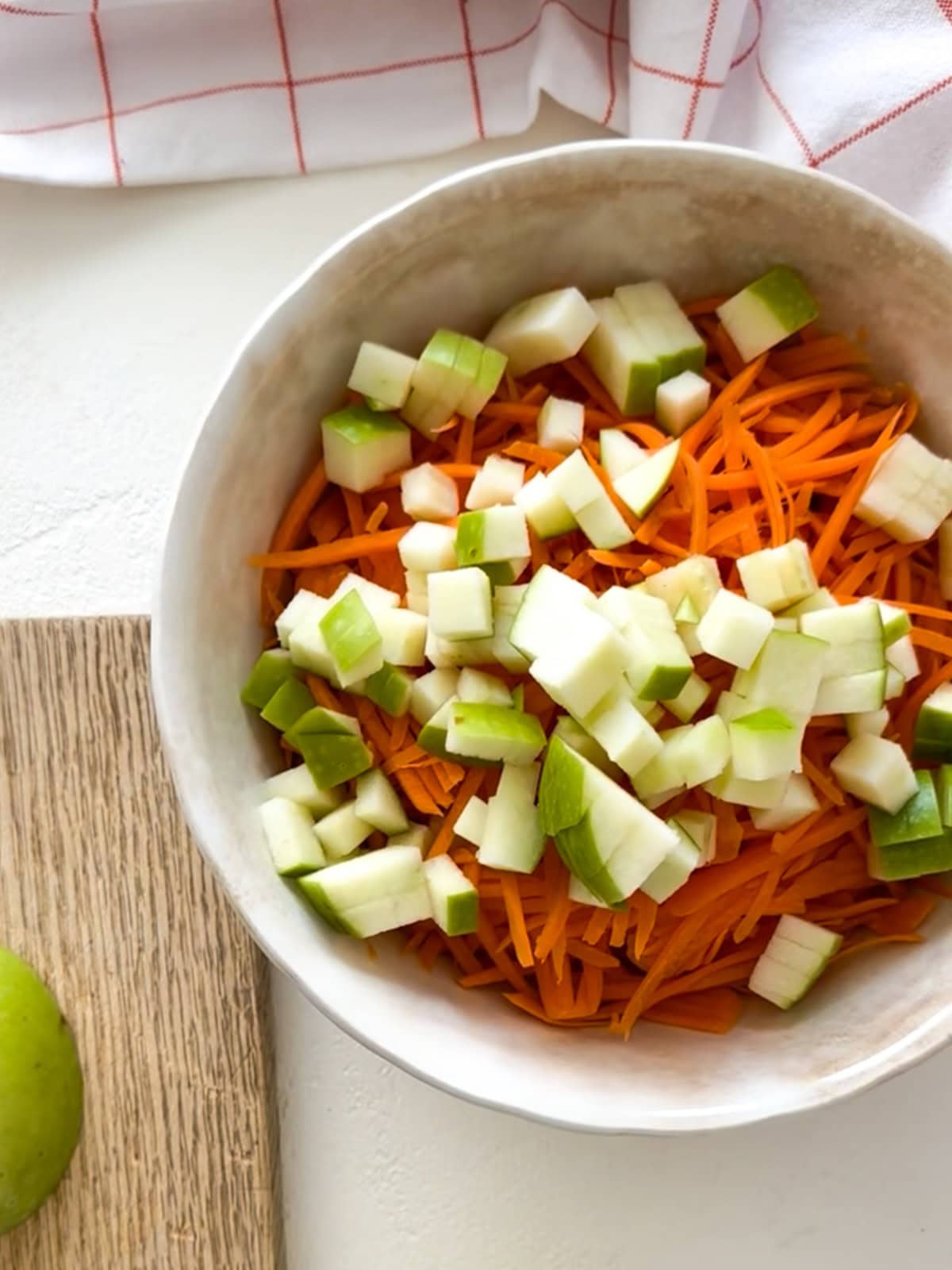 dice apples and shredded carrots in a bowl for salad.