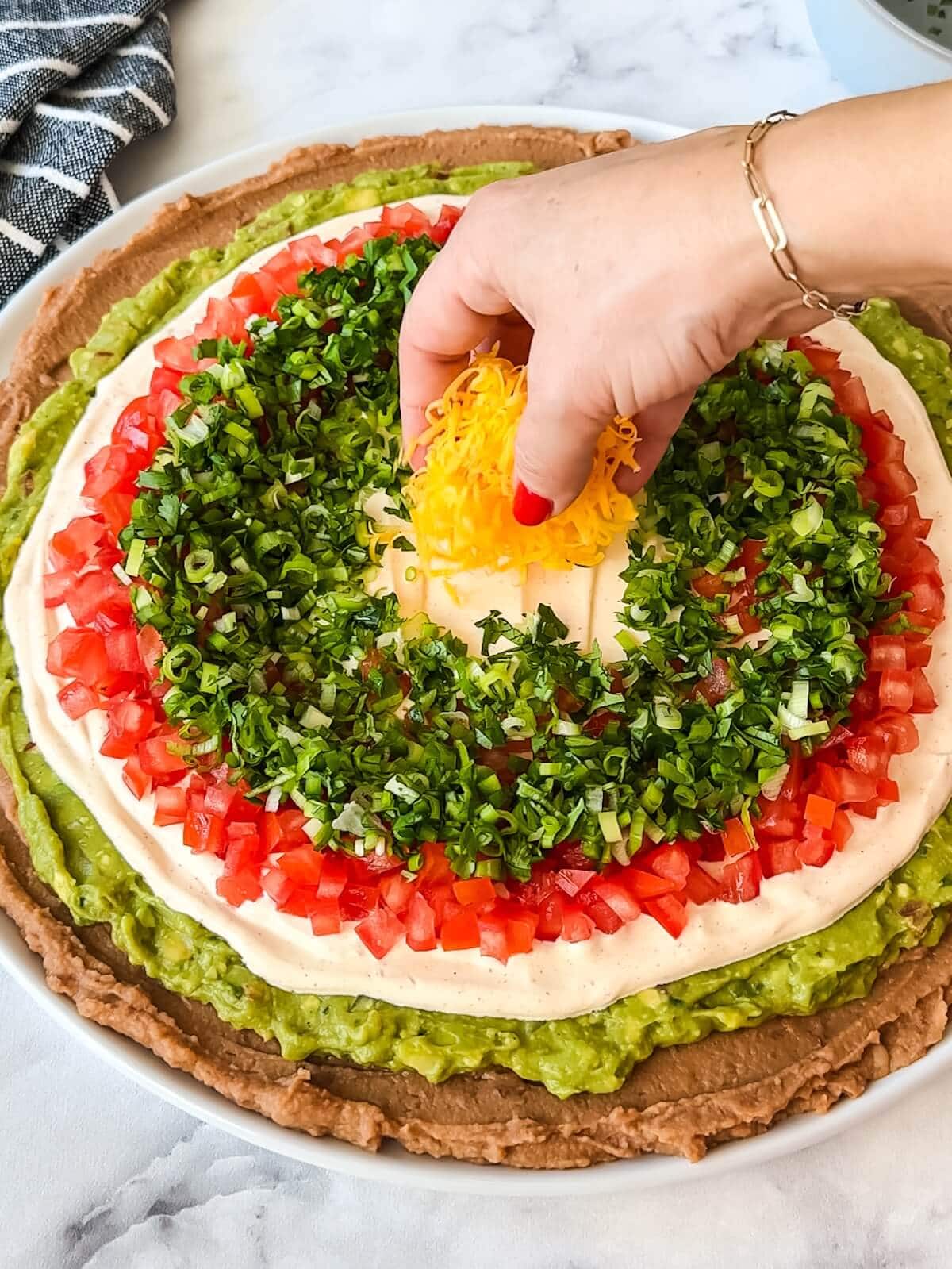 Adding the center circle of cheese to the dip before the last ring of olives.