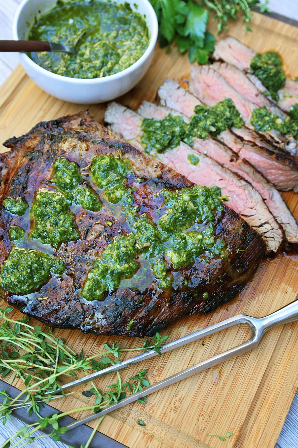 Grilled flank steak with salsa verde sliced on a cutting board