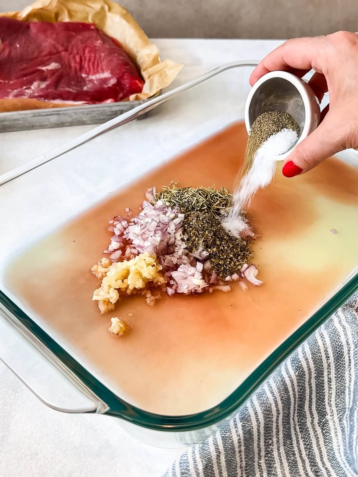 mixing vinegar, lemon juice, shallots, garlic, and herbs in a dish for steak marinade.