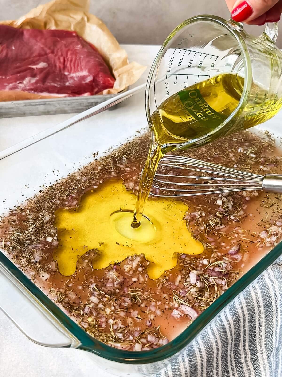 adding olive oil to flank steak marinade in a dish.
