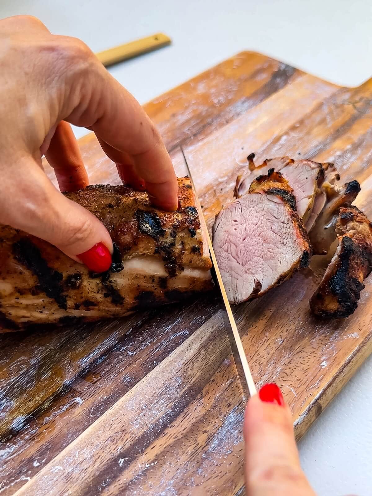 slicing grilled pork tenderloin before serving.