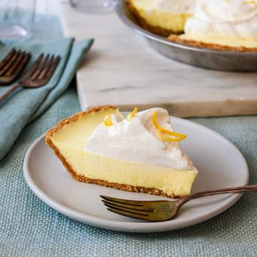 Slice of lemon icebox pie on a white plate with a fork.