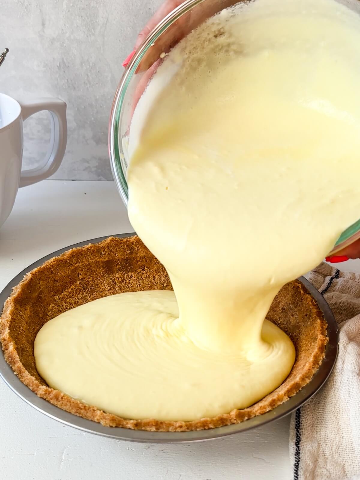 Adding lemon icebox pie filling to the crust in the pie tin.