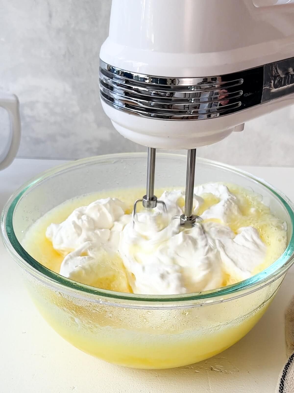 Folding whipped cream into the lemon filling with a mixer.