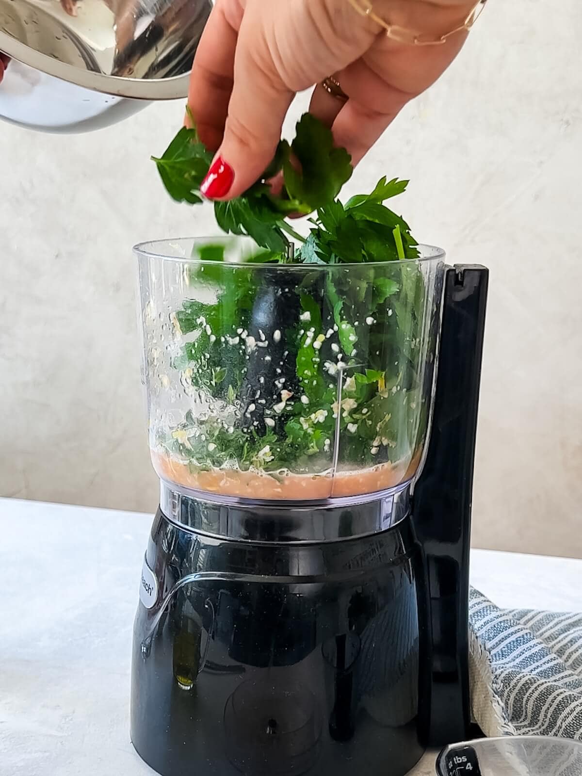 adding herbs to the Italian salsa verde mixture in mini food processor