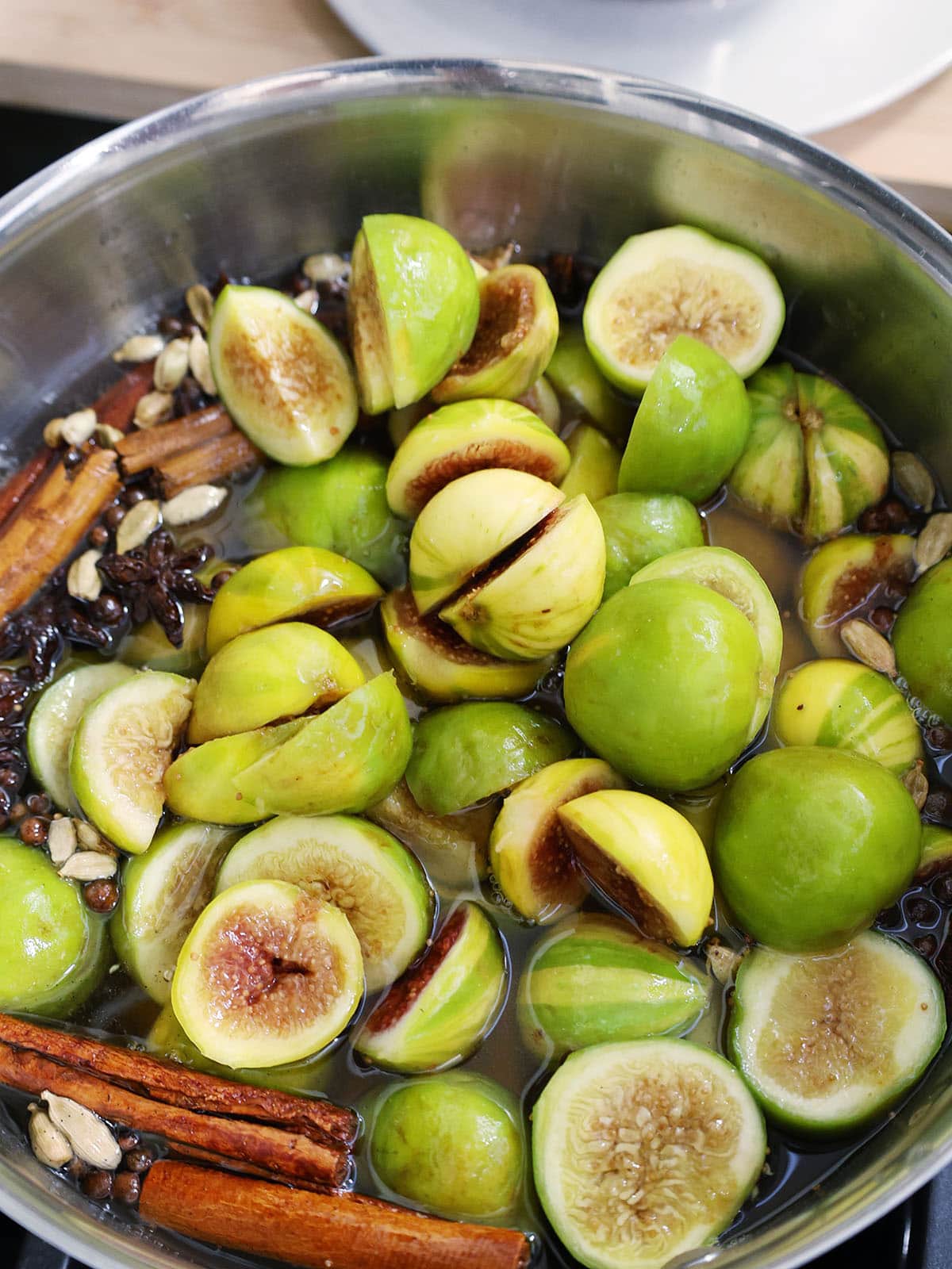 fresh figs simmering in syrup with whole spices.
