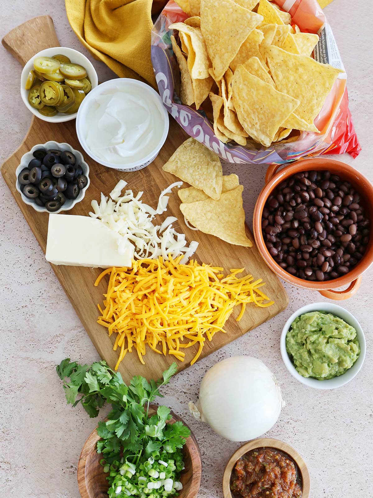 Ingredients for oven baked nachos including cheeses, onion, and black beans.