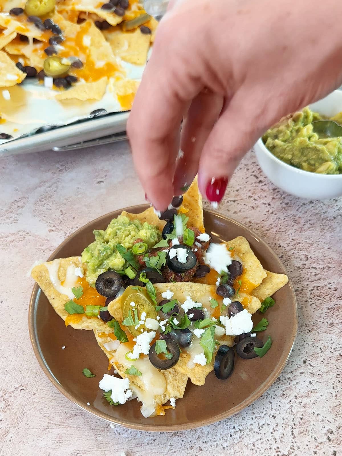 topping oven baked nachos with flavorful toppings like guacamole and olives.