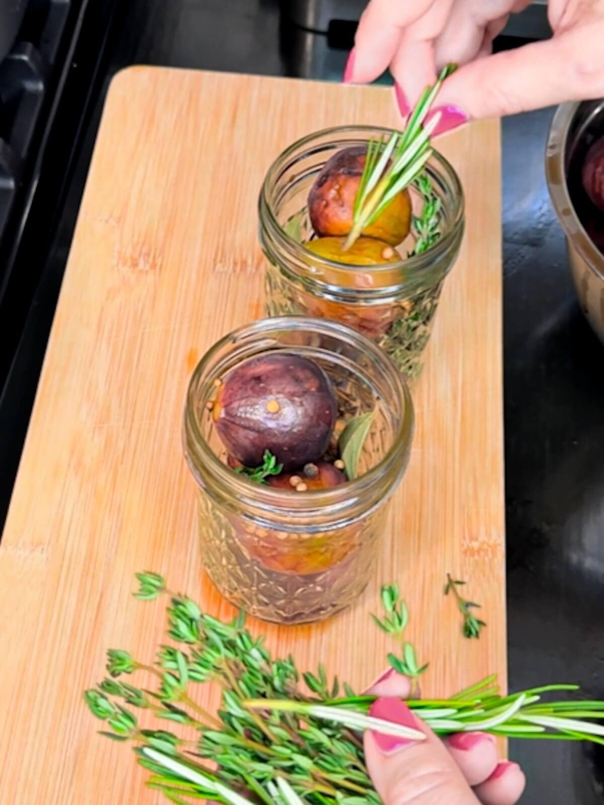 adding fresh herbs to jars of preserved figs