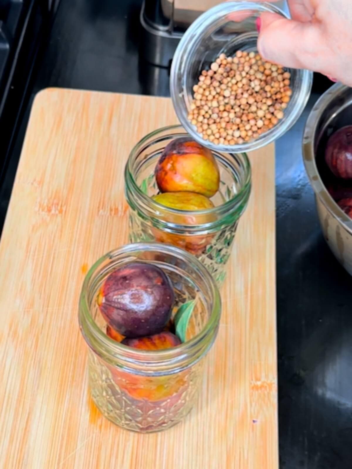 adding spices to jars of figs for canning