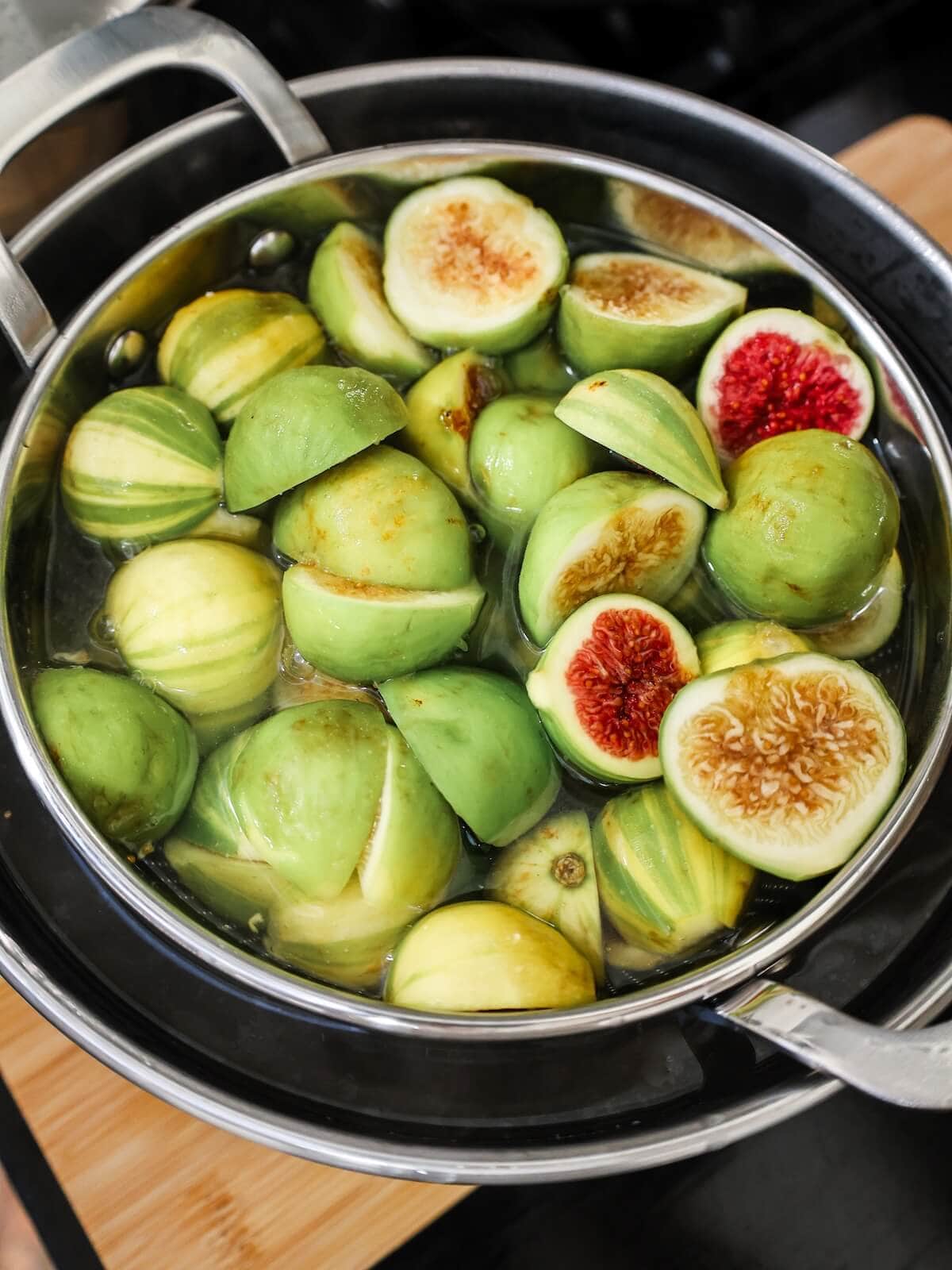 blanching fresh figs in water to prepare them for preserving.