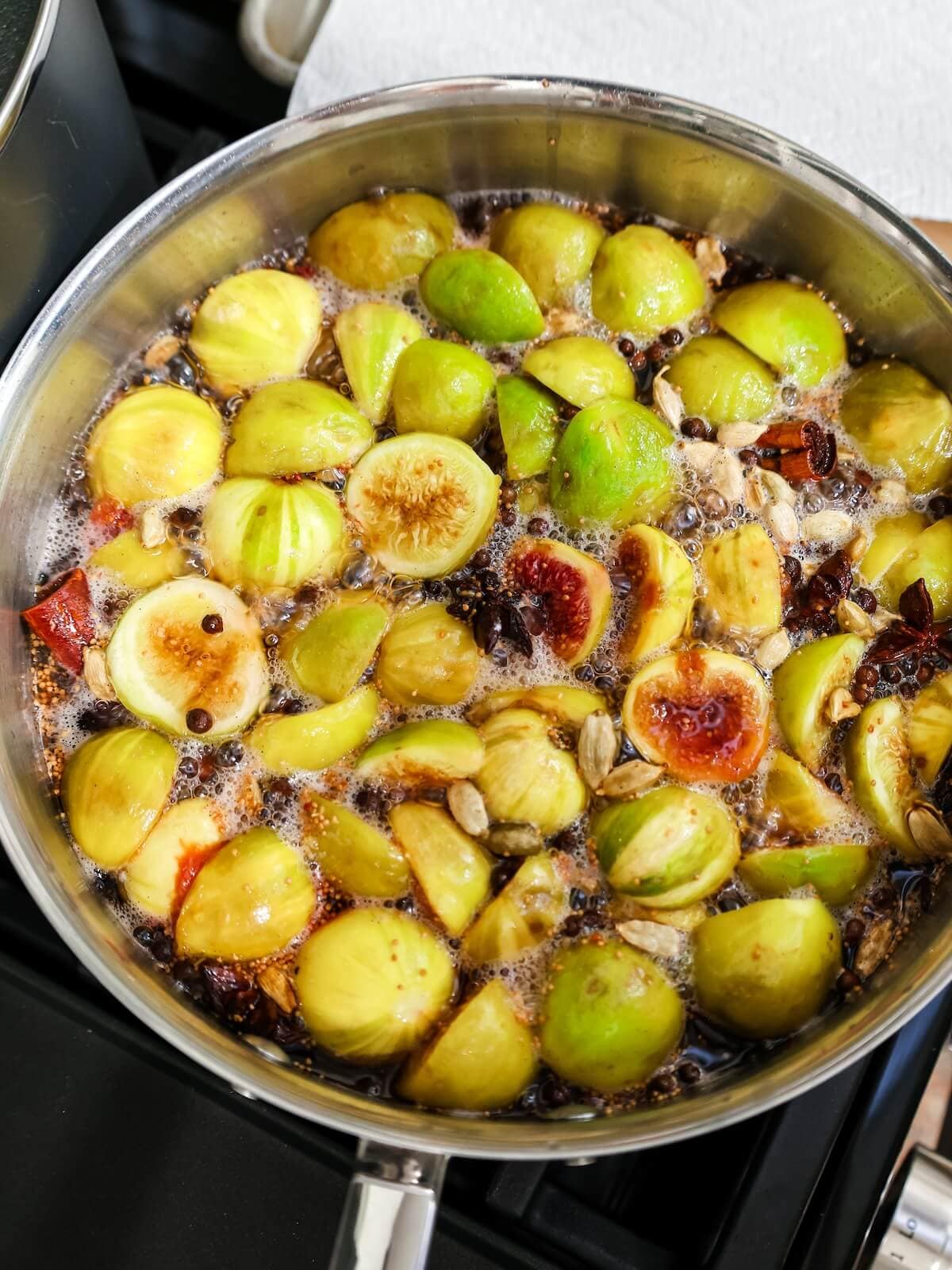 Simmering figs in syrup in a saucepan.
