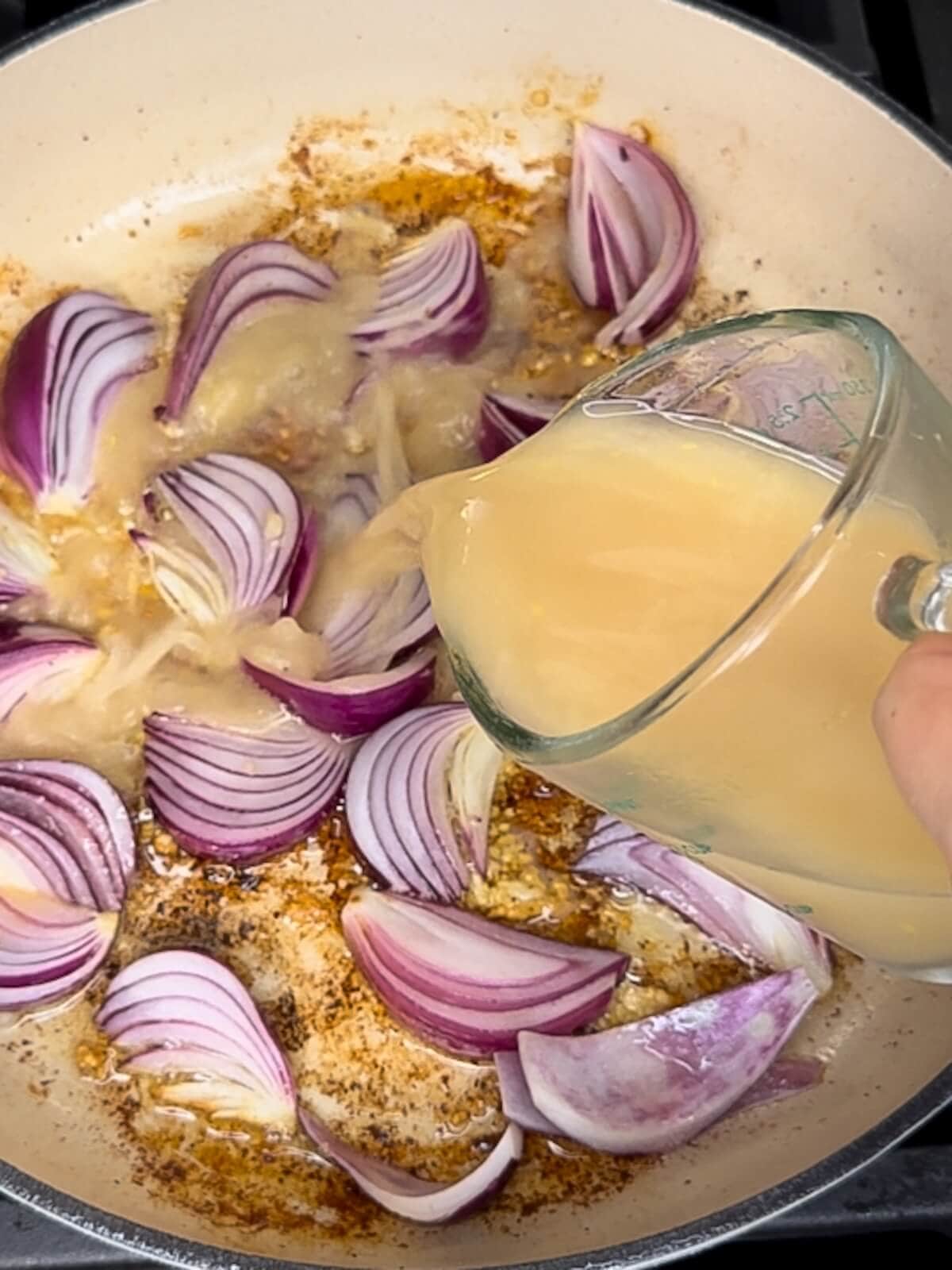 adding broth and cornstarch to onions in pan to deglaze.