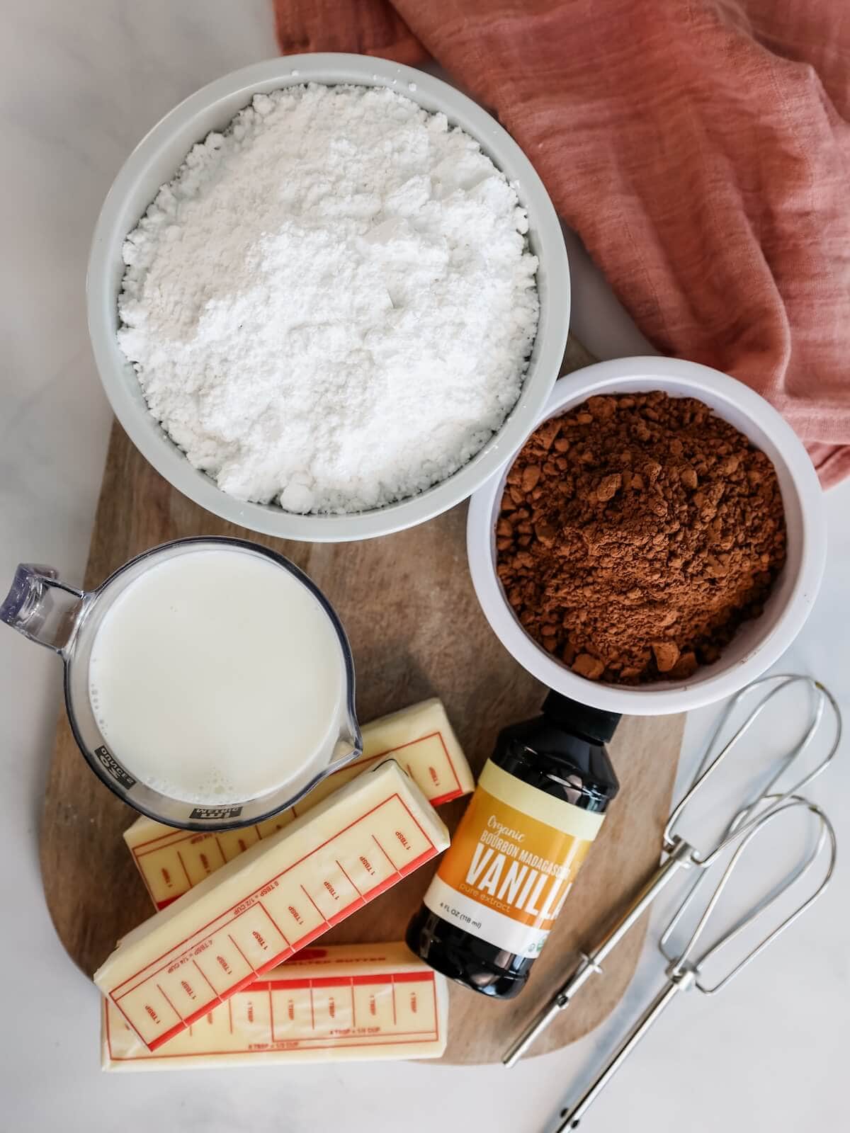 Ingredients for Rich Milk Chocolate Frosting including butter, vanilla, milk, cocoa powder, and confectioners' sugar.