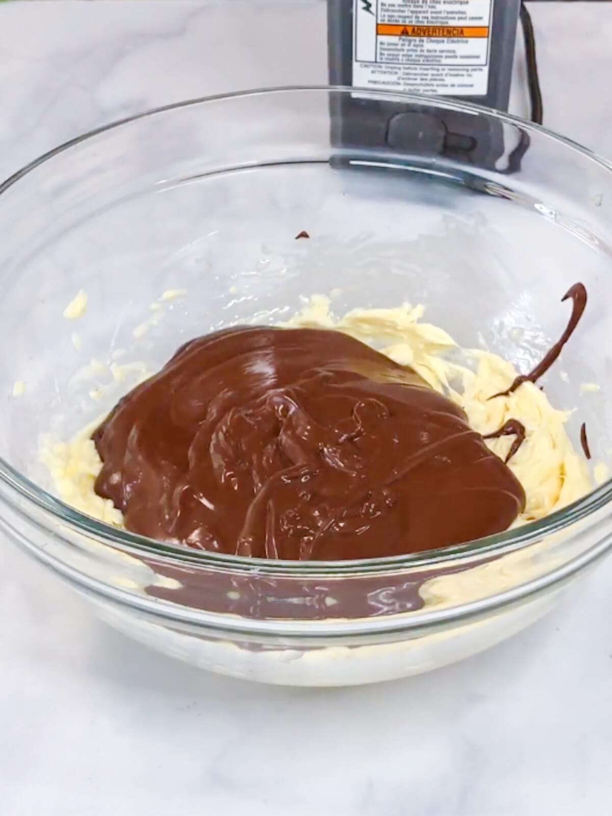 Adding chocolate mixture to beaten butter.