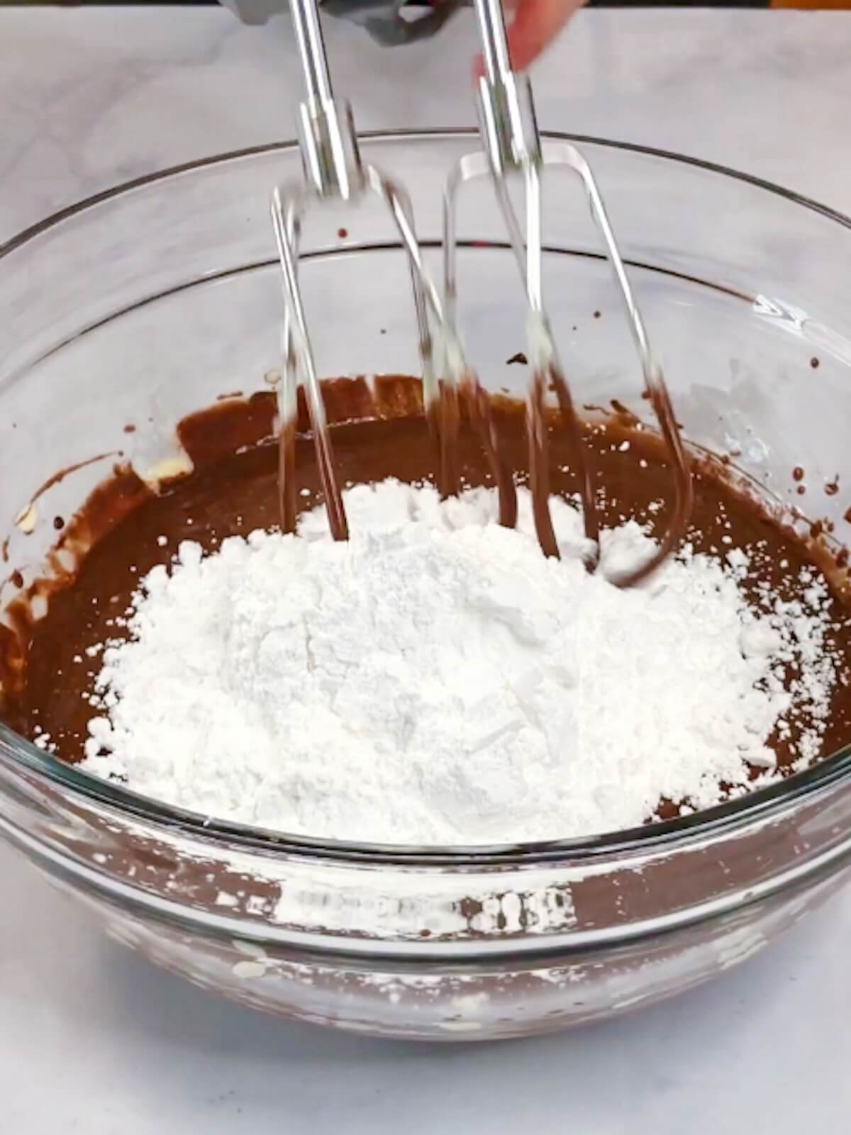 Adding powdered sugar to chocolate frosting mixture.