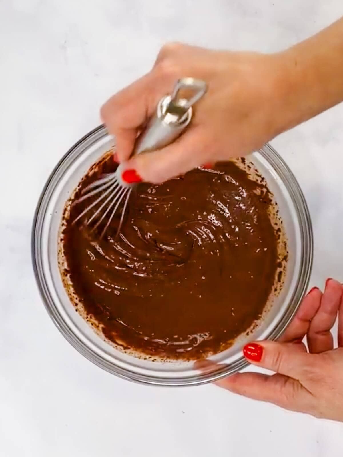 Hand stirring butter, cocoa, and milk.