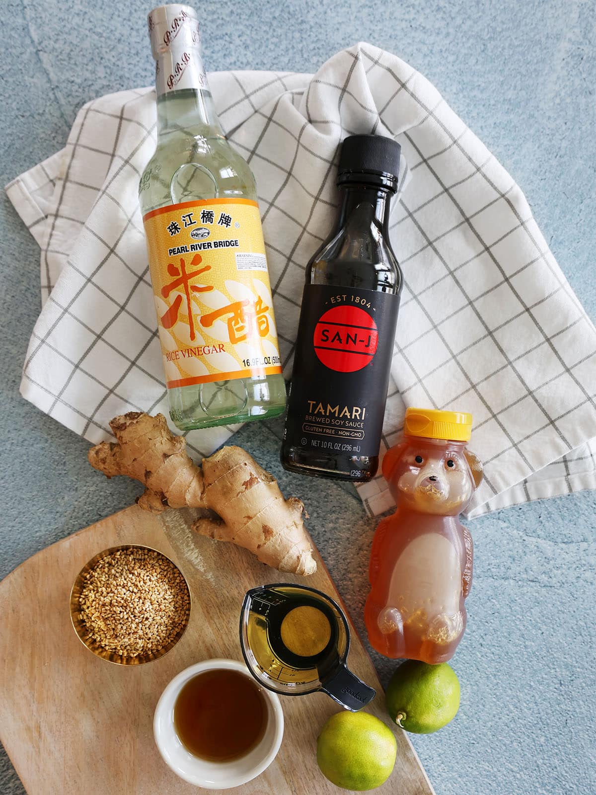 Ingredients for ginger sesame dressing including rice vinegar, tamari, honey, ginger, limes, and more.