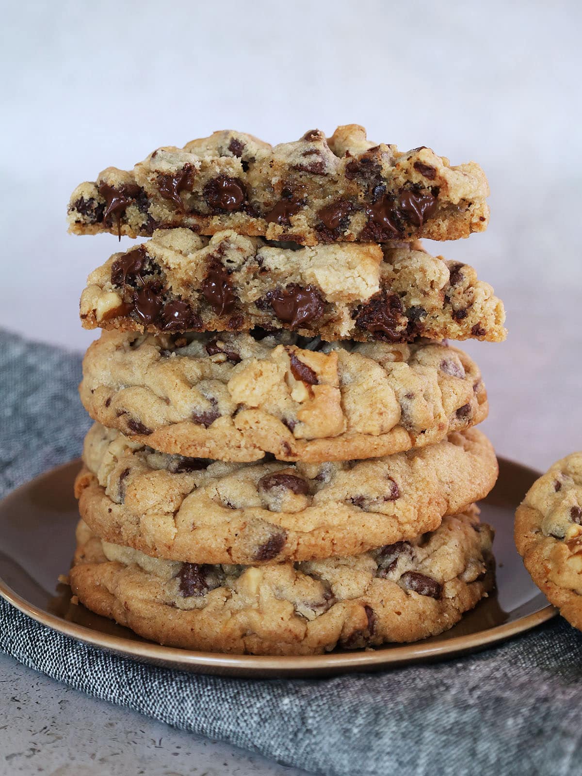 stack of walnut chocolate chip cookies with one cookie broken open.