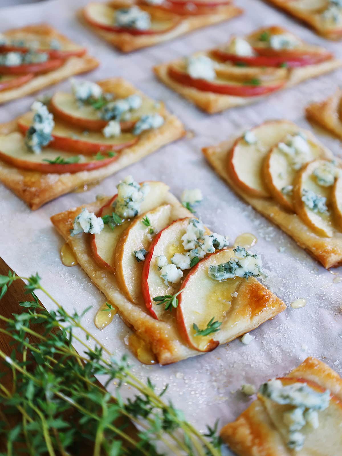 apple tarts with blue cheese on parchment paper with a drizzle of honey