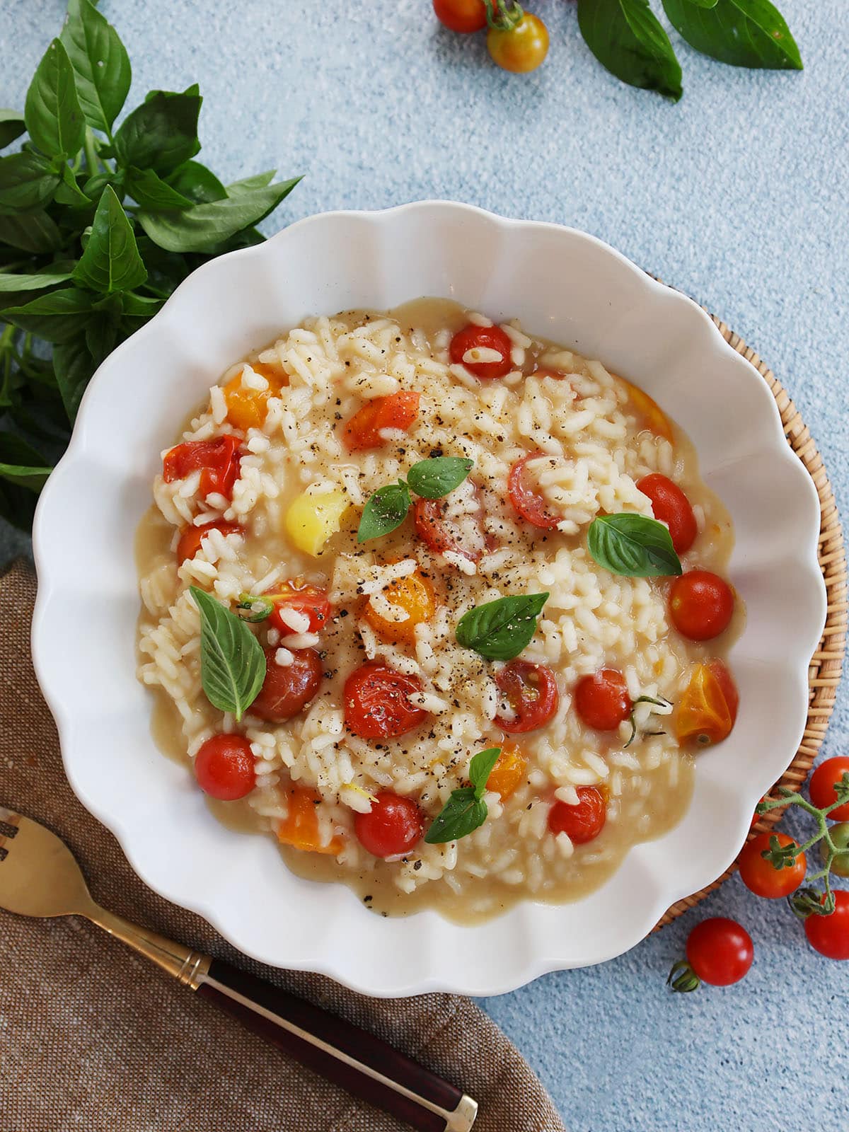 overhead shot of risotto with cherry tomatoes and basil