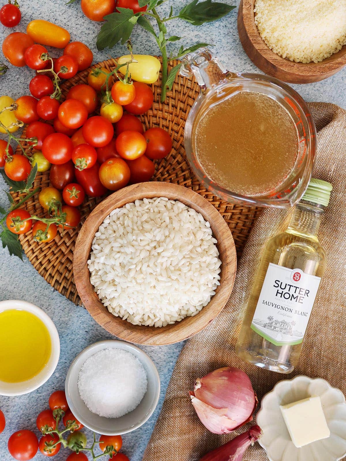 ingredients for tomato risotto including arborio rice, broth, wine, cheese, salt, shallot, butter and olive oil.