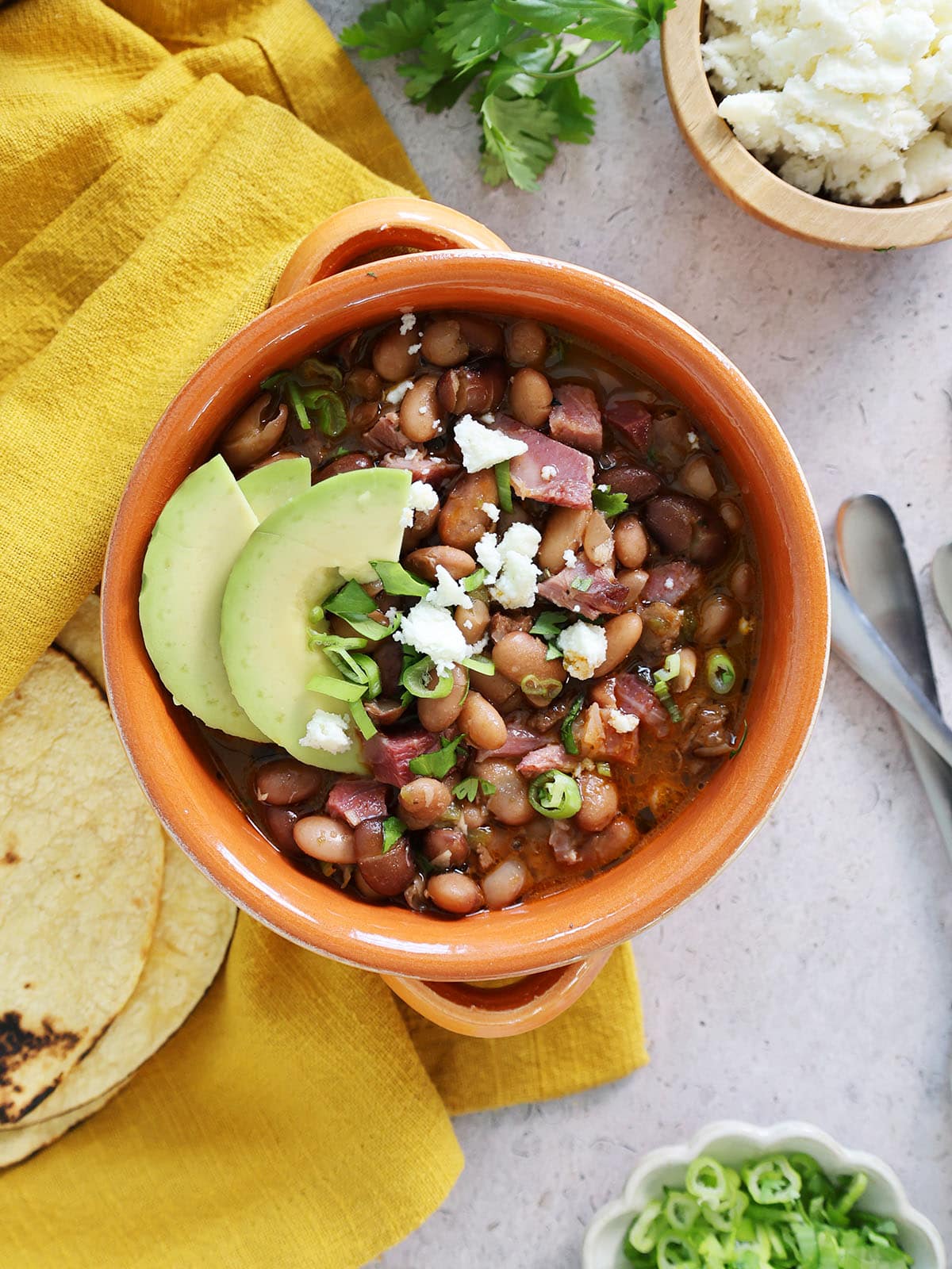 charro beans in a bowl with sliced avocado.