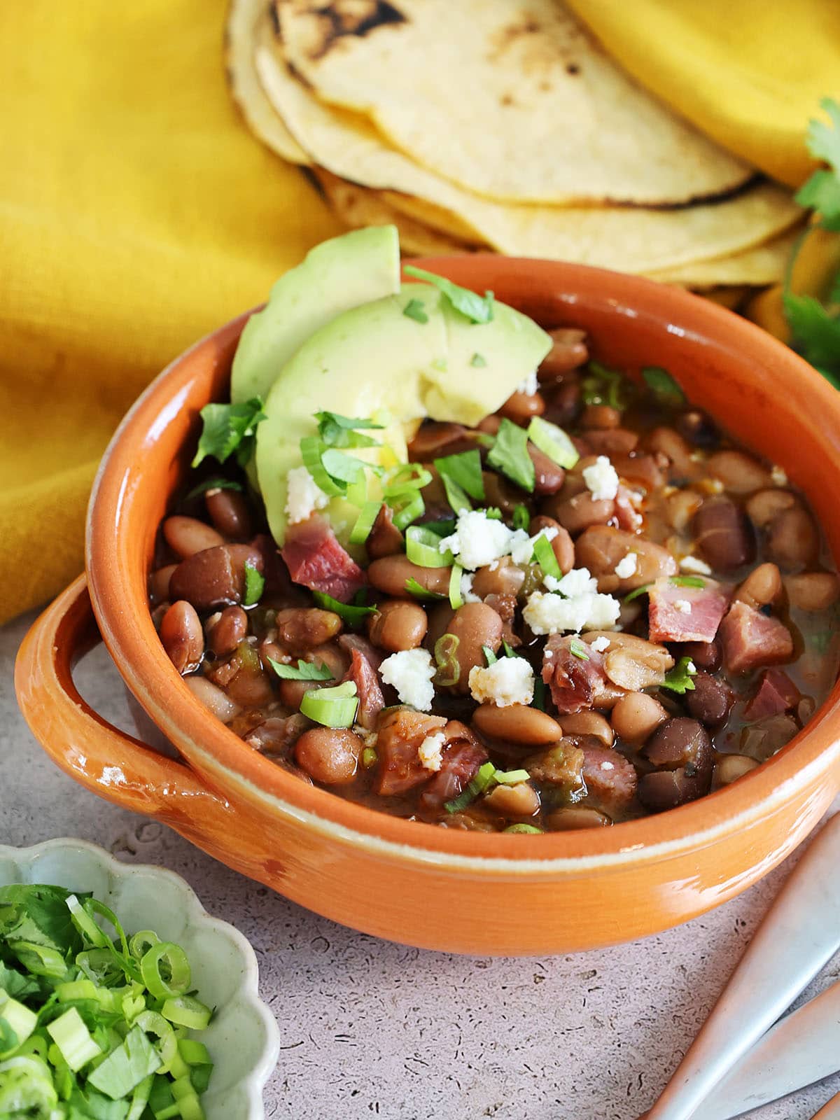 bowl of charro beans with avocado and cotija cheese.
