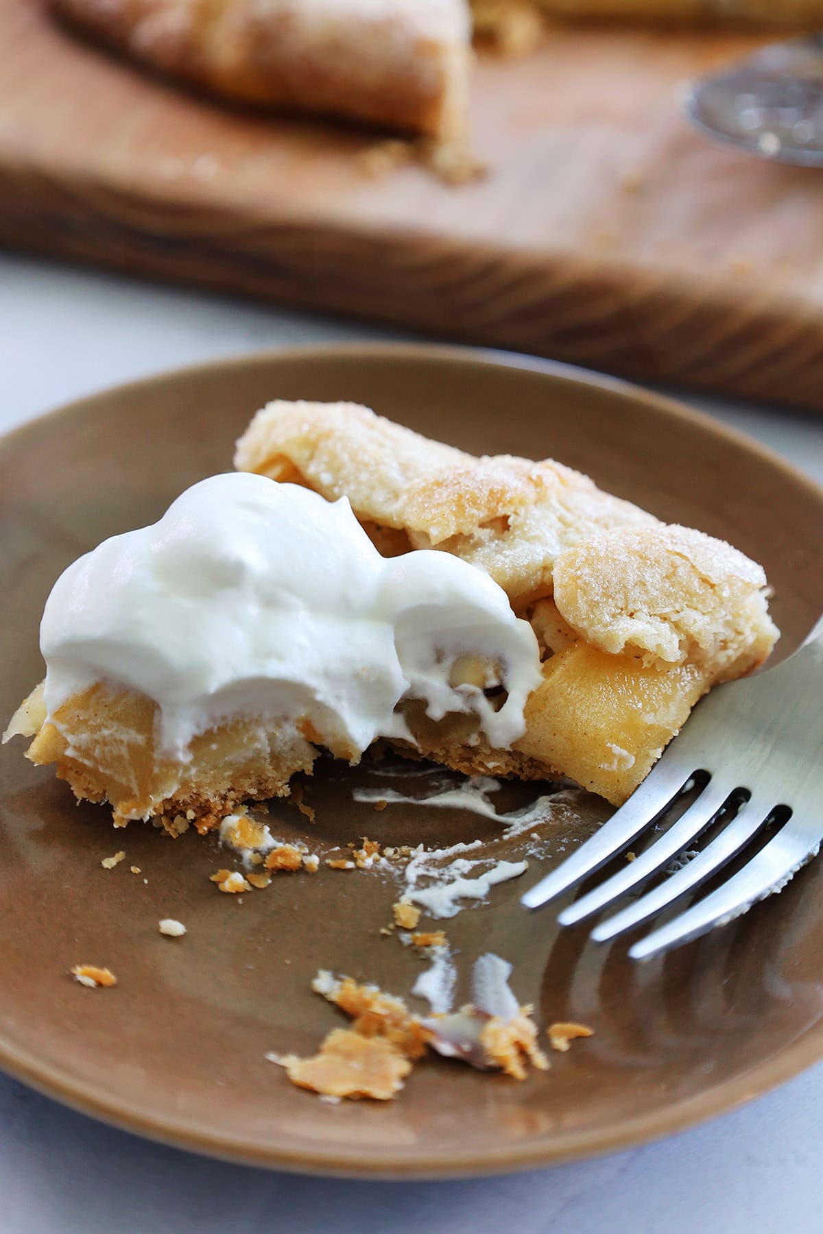 slice of apple tart with frangipane with a few bites out of it and a fork on a plate.