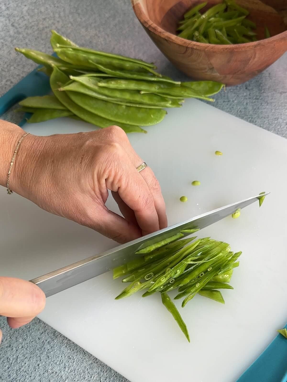 thinly slicing snow peas on a bias to an asian slaw