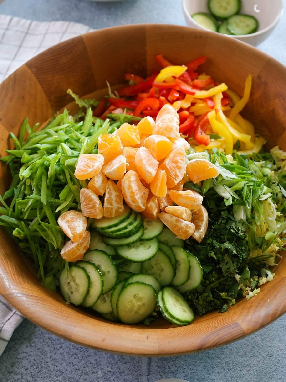 asian salad ready to be tossed and mixed in a wood bowl