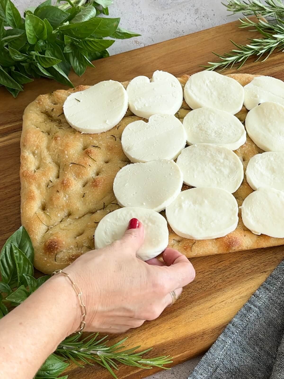 placing fresh mozzarella slices on caprese focaccia