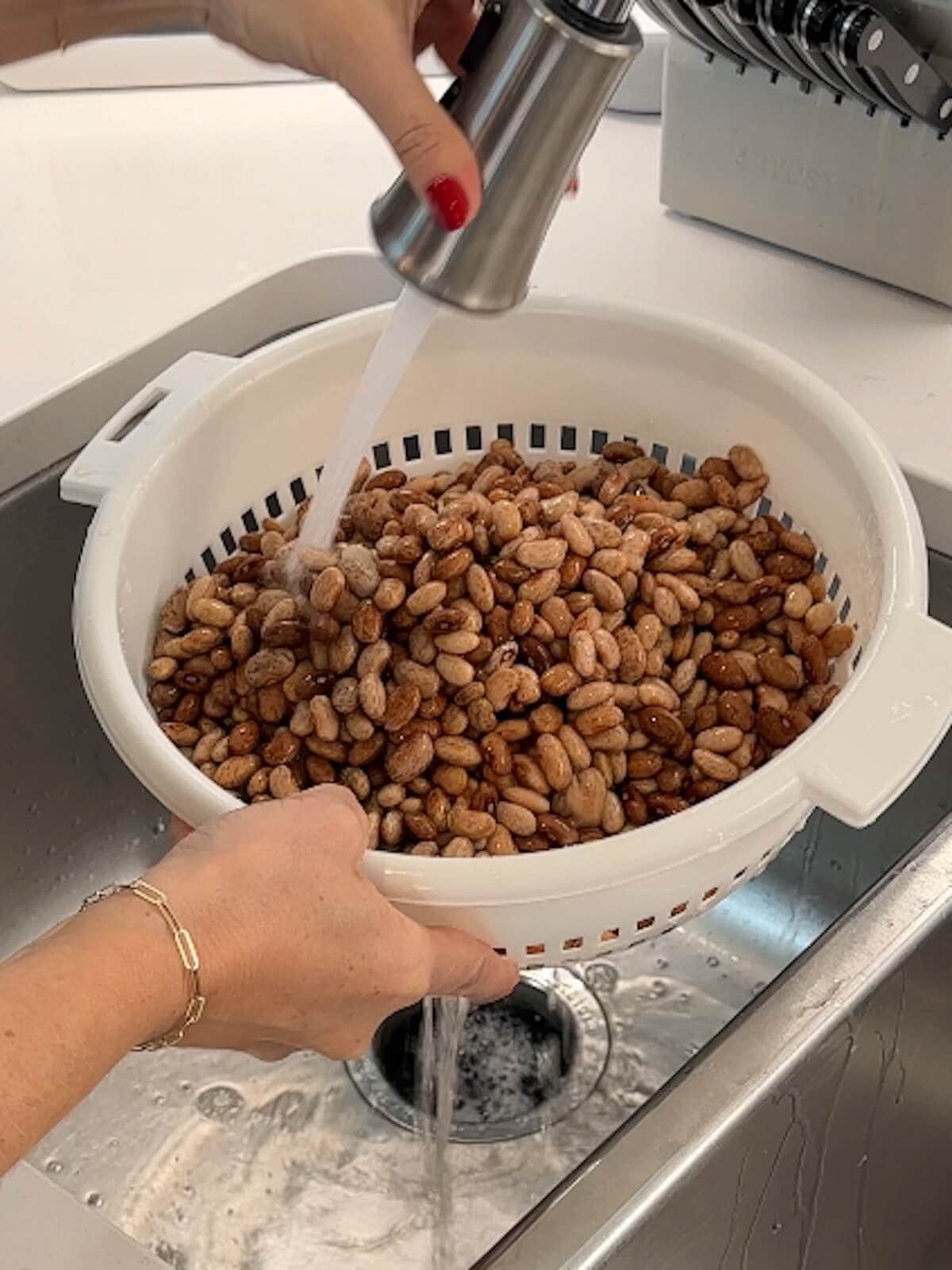 Rinsing soaked pinto beans in a colandar.