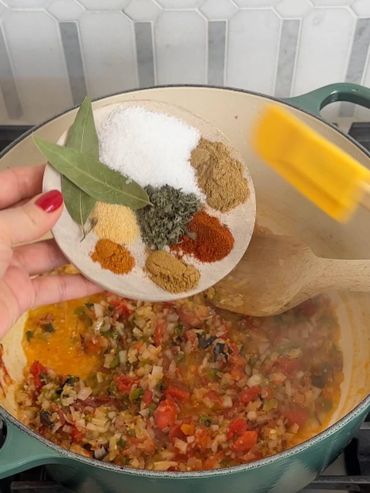 Adding spices, salt and bay leaves to charro beans in a pot.