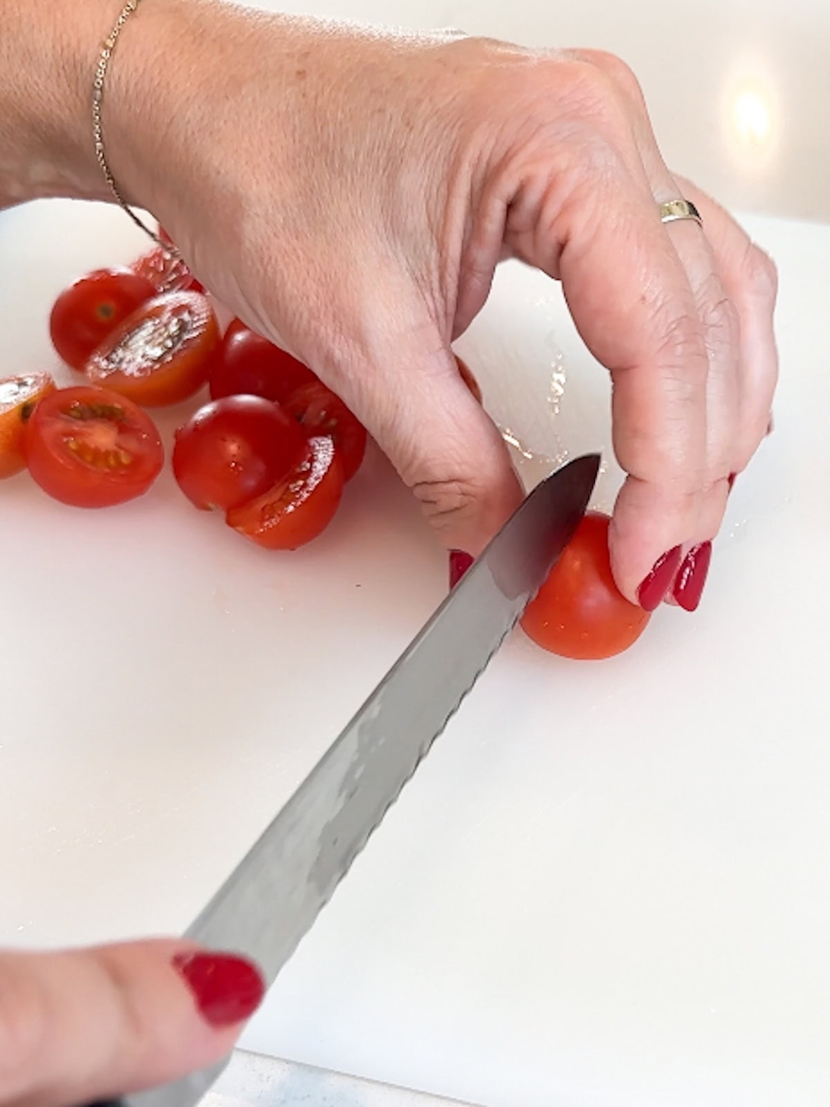 Cut cherry tomatoes in half for tomato risotto.