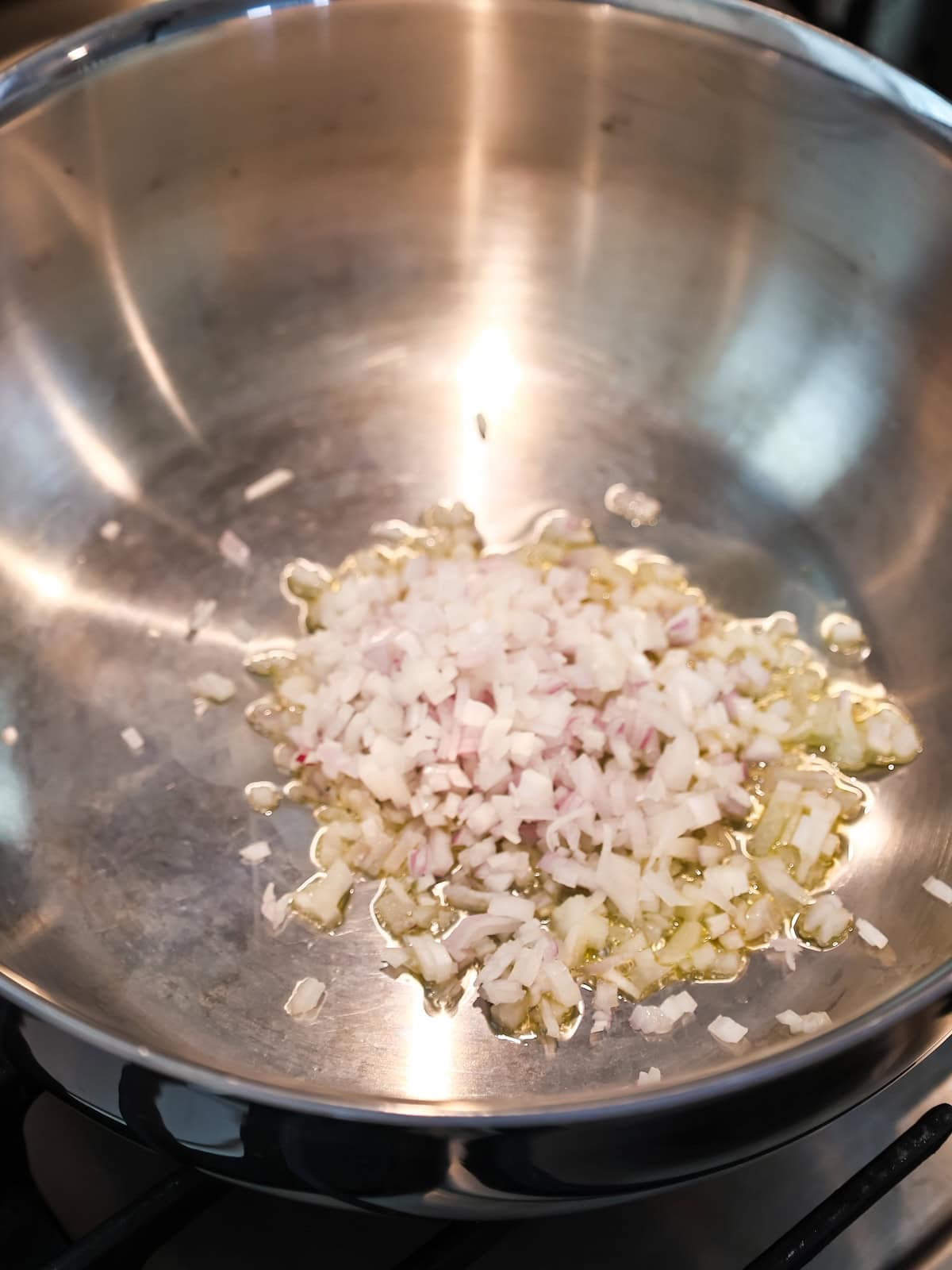 adding olive oil and shallots to a pan to start risotto.