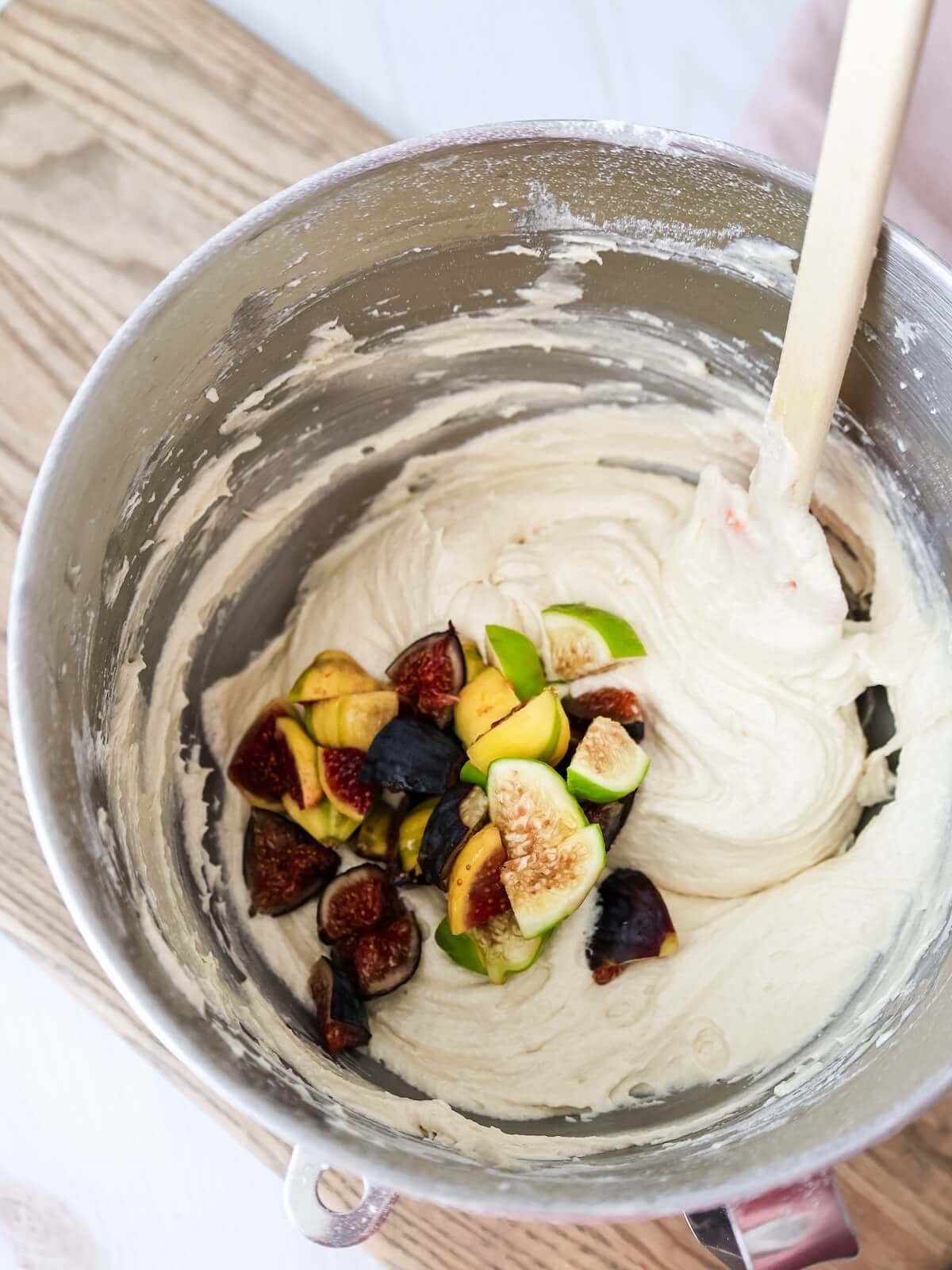 Stirring fresh figs into cake batter by hand with a silicone spatula.