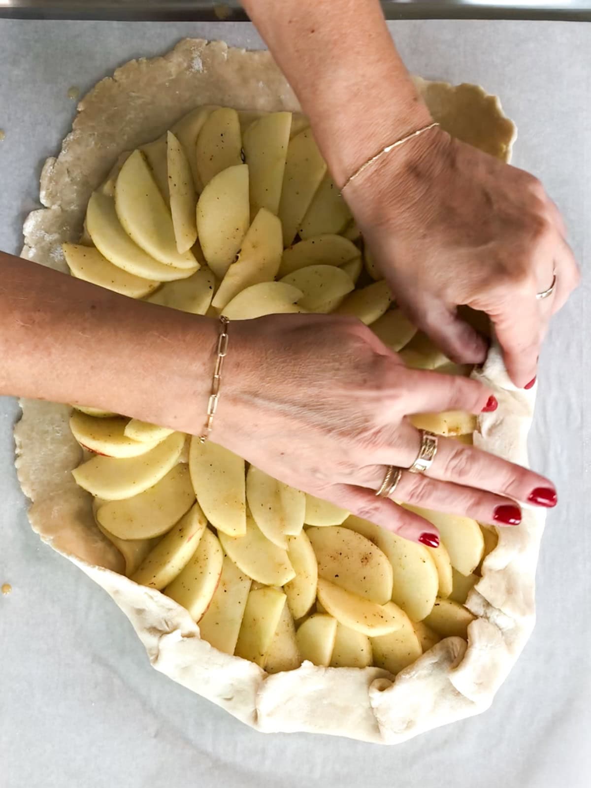folding and crimping the outside edges of a rustic apple tart.