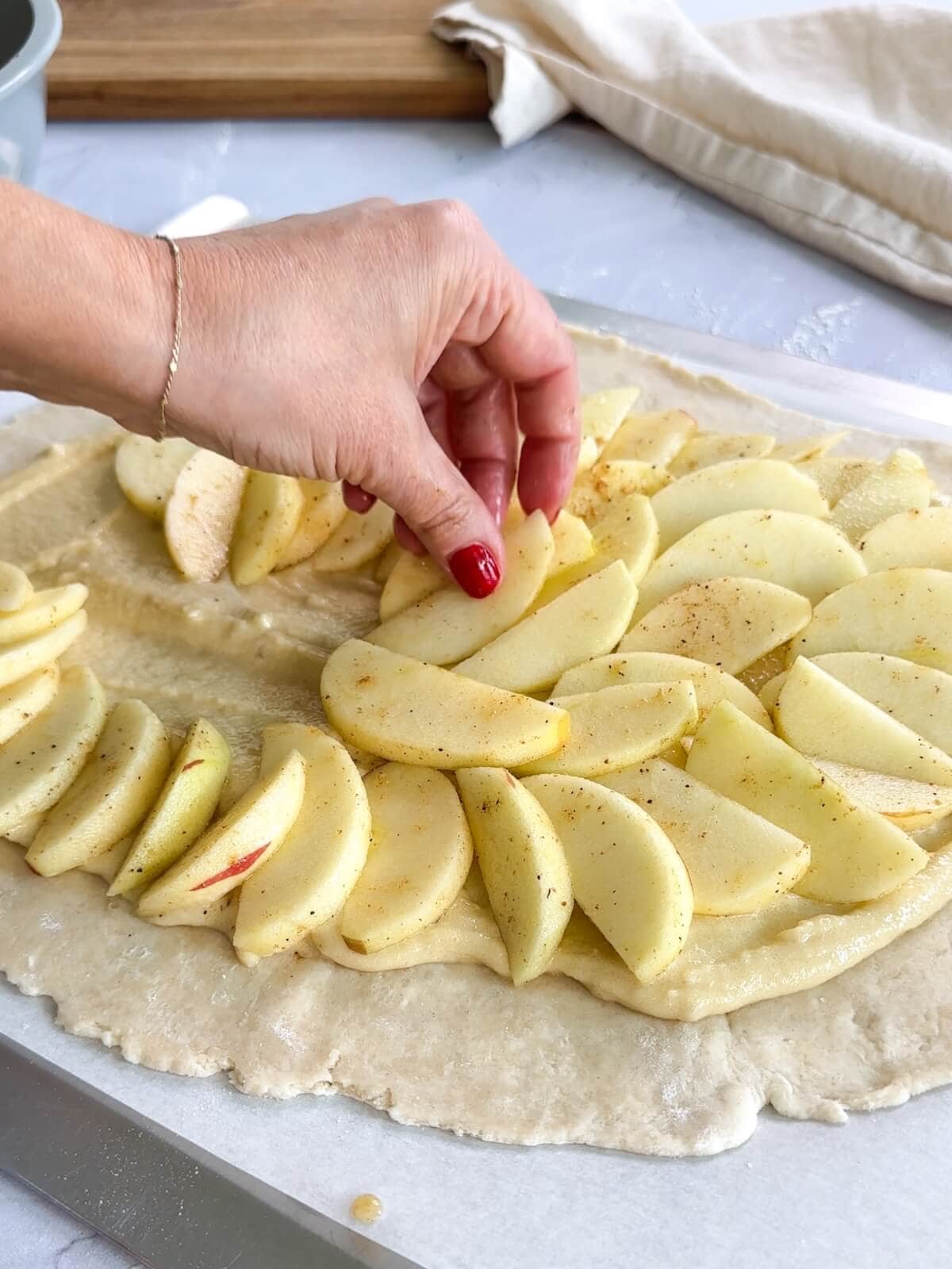 placing apple slices on frangipane over an apple tart crust.