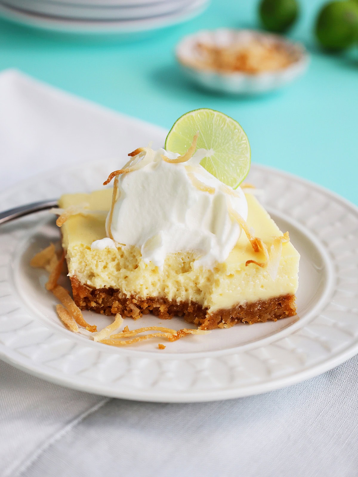 Coconut key lime pie bars serving on a plate with a few bites eaten.
